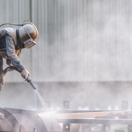 A man shotblasting a large piece of machinery