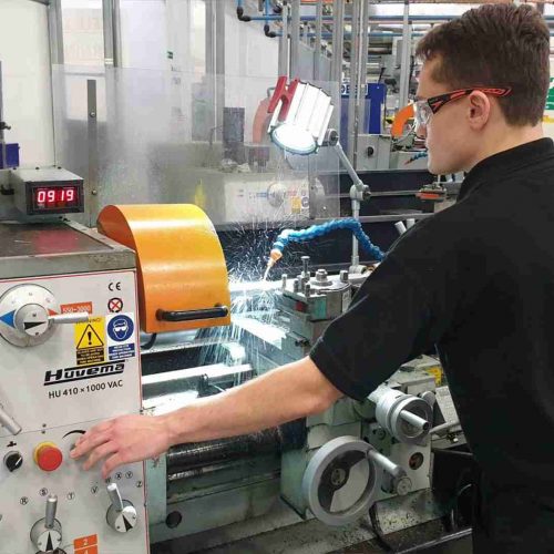 A person using a manual turning machine with a hose attachment